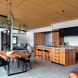 Photo of a mid-sized contemporary galley open plan kitchen in Melbourne with concrete floors, grey floor, a drop-in sink, flat-panel cabinets, medium wood cabinets, white splashback, stainless steel appliances, with island and grey benchtop.