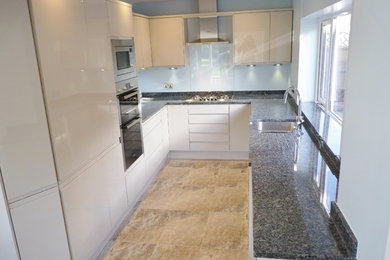 Inspiration for a medium sized contemporary galley open plan kitchen in Sussex with a submerged sink, flat-panel cabinets, beige cabinets, granite worktops, glass sheet splashback, integrated appliances, porcelain flooring and no island.