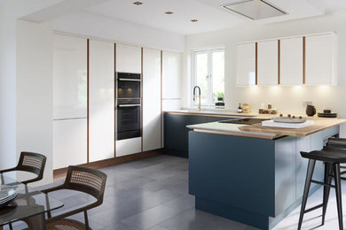 Photo of a modern kitchen/diner in Edinburgh with flat-panel cabinets, blue cabinets, white splashback, integrated appliances, a breakfast bar, white worktops and a drop ceiling.