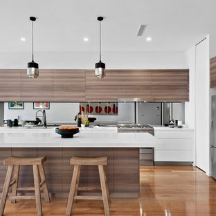 This is an example of a mid-sized contemporary open plan kitchen in Melbourne with a double-bowl sink, quartz benchtops, mirror splashback, stainless steel appliances, with island, white benchtop, flat-panel cabinets, dark wood cabinets and medium hardwood floors.