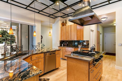 Enclosed kitchen - mid-sized contemporary u-shaped light wood floor and beige floor enclosed kitchen idea in Boise with an undermount sink, flat-panel cabinets, medium tone wood cabinets, granite countertops, black backsplash, stone slab backsplash, stainless steel appliances and two islands