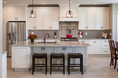 Example of a large classic porcelain tile and beige floor kitchen design in Seattle with an undermount sink, raised-panel cabinets, white cabinets, granite countertops, brown backsplash, subway tile backsplash, stainless steel appliances and an island