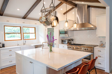 Eat-in kitchen - mid-sized transitional l-shaped medium tone wood floor and brown floor eat-in kitchen idea in Santa Barbara with a farmhouse sink, shaker cabinets, white cabinets, marble countertops, white backsplash, subway tile backsplash, stainless steel appliances, an island and white countertops