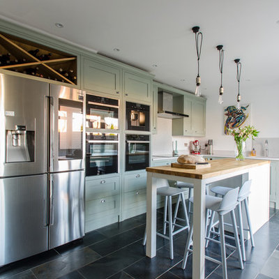 Mid-sized transitional l-shaped kitchen photo in Kent with an undermount sink, recessed-panel cabinets, green cabinets, gray backsplash, stainless steel appliances and an island