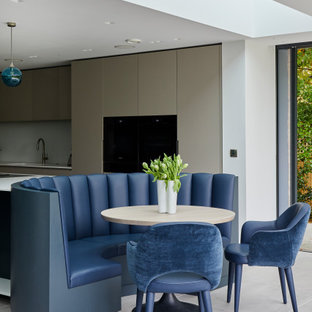 This is an example of a large contemporary l-shaped open plan kitchen in Kent with flat-panel cabinets, beige cabinets, engineered stone countertops, an island and white worktops.