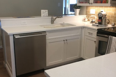 Example of an u-shaped porcelain tile and multicolored floor eat-in kitchen design in Philadelphia with a double-bowl sink, shaker cabinets, white cabinets, quartz countertops, beige backsplash, ceramic backsplash, stainless steel appliances and no island