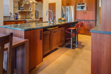 Large trendy u-shaped travertine floor eat-in kitchen photo in Albuquerque with flat-panel cabinets, dark wood cabinets, an island, granite countertops, multicolored backsplash, glass tile backsplash, an undermount sink and stainless steel appliances