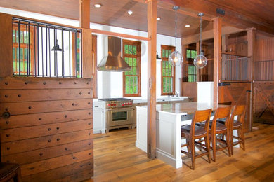 Example of a large cottage galley light wood floor and brown floor open concept kitchen design in Other with a farmhouse sink, flat-panel cabinets, gray cabinets, marble countertops, white backsplash, subway tile backsplash, paneled appliances and an island