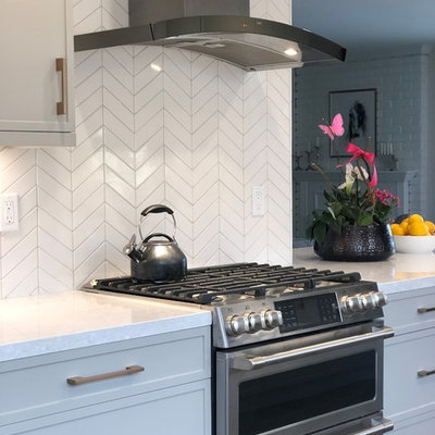 Example of a small transitional galley medium tone wood floor and brown floor open concept kitchen design in San Francisco with an undermount sink, shaker cabinets, quartz countertops, white backsplash, ceramic backsplash, stainless steel appliances, a peninsula, white countertops and gray cabinets