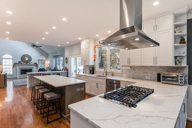 Large elegant galley medium tone wood floor and brown floor eat-in kitchen photo in Other with an undermount sink, shaker cabinets, white cabinets, quartzite countertops, multicolored backsplash, glass sheet backsplash, stainless steel appliances, an island and white countertops