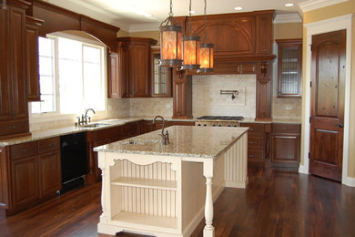 Example of a classic u-shaped eat-in kitchen design in Chicago with an undermount sink, raised-panel cabinets, dark wood cabinets, granite countertops, beige backsplash, stone tile backsplash and stainless steel appliances