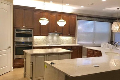 マイアミにある高級な中くらいなトランジショナルスタイルのおしゃれなキッチン (アンダーカウンターシンク、ガラスタイルのキッチンパネル、シルバーの調理設備、淡色無垢フローリング) の写真