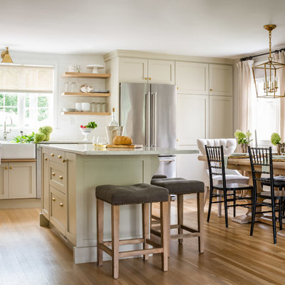 Eat-in kitchen - mid-sized transitional l-shaped brown floor and medium tone wood floor eat-in kitchen idea in Boston with a farmhouse sink, shaker cabinets, beige cabinets, marble countertops, white backsplash, subway tile backsplash, stainless steel appliances, an island and white countertops