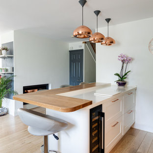 Large traditional u-shaped open plan kitchen in Hertfordshire with an integrated sink, shaker cabinets, grey cabinets, quartzite benchtops, metallic splashback, glass tile splashback, light hardwood floors, a peninsula and white benchtop.