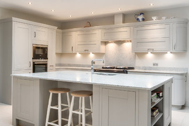 Design ideas for a farmhouse kitchen in Gloucestershire with shaker cabinets, grey splashback, black appliances and an island.