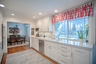 Example of a transitional galley enclosed kitchen design in San Francisco with shaker cabinets, white cabinets, quartzite countertops, gray backsplash, subway tile backsplash and stainless steel appliances