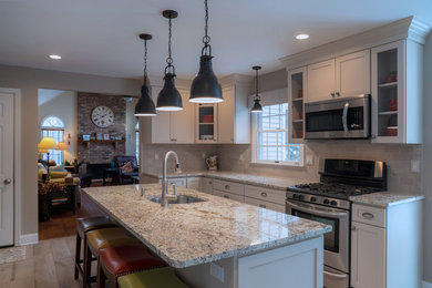 Mid-sized transitional l-shaped porcelain tile and gray floor eat-in kitchen photo in New York with a single-bowl sink, recessed-panel cabinets, white cabinets, granite countertops, gray backsplash, limestone backsplash, stainless steel appliances, an island and gray countertops