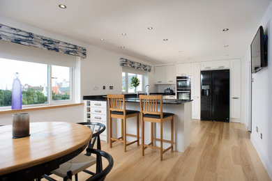 Foto på ett mellanstort funkis kök, med en dubbel diskho, skåp i shakerstil, granitbänkskiva, grått stänkskydd och ljust trägolv