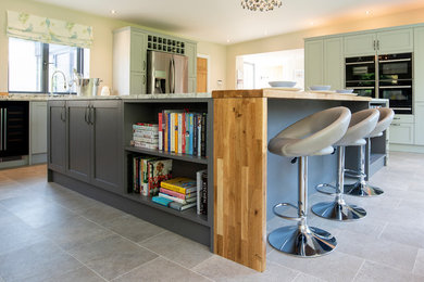 Diseño de cocina minimalista grande con armarios estilo shaker, puertas de armario grises, encimera de madera, electrodomésticos de acero inoxidable, suelo laminado, una isla y suelo gris