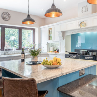 Design ideas for a large traditional l-shaped kitchen in Essex with an island, recessed-panel cabinets, white cabinets, blue splashback, glass sheet splashback, beige floors and multicoloured worktops.