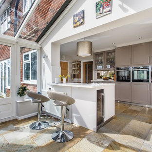 Design ideas for a mid-sized country u-shaped eat-in kitchen in Sussex with shaker cabinets, grey cabinets, quartzite benchtops, metallic splashback, limestone splashback, travertine floors, yellow benchtop, stainless steel appliances and a peninsula.