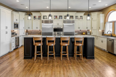 Elegant u-shaped medium tone wood floor kitchen photo in Other with an undermount sink, shaker cabinets, beige cabinets, gray backsplash, matchstick tile backsplash, stainless steel appliances, an island and gray countertops