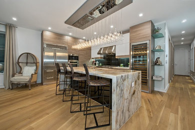 Стильный дизайн: угловая кухня-гостиная в современном стиле с светлыми деревянными фасадами, техникой из нержавеющей стали, светлым паркетным полом, островом, бежевым полом и белой столешницей - последний тренд