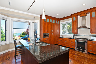 Example of a large transitional l-shaped dark wood floor and brown floor enclosed kitchen design in Vancouver with an island, an undermount sink, shaker cabinets, dark wood cabinets, quartz countertops, beige backsplash, ceramic backsplash, stainless steel appliances and black countertops