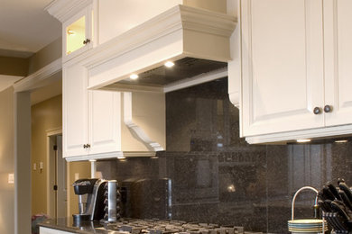 Example of a large classic u-shaped porcelain tile eat-in kitchen design in Other with raised-panel cabinets, granite countertops, black backsplash, stone slab backsplash, stainless steel appliances, an undermount sink, white cabinets and an island