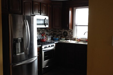 Example of a mid-sized transitional u-shaped vinyl floor kitchen design in Philadelphia with recessed-panel cabinets, dark wood cabinets, granite countertops, multicolored backsplash, mosaic tile backsplash, stainless steel appliances and an undermount sink