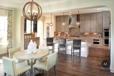 Example of a large transitional u-shaped medium tone wood floor open concept kitchen design in Jacksonville with a double-bowl sink, flat-panel cabinets, gray cabinets, granite countertops, brown backsplash, glass tile backsplash, stainless steel appliances and an island