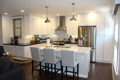 Example of a mid-sized transitional u-shaped dark wood floor and brown floor eat-in kitchen design in Los Angeles with an undermount sink, white cabinets, quartz countertops, white backsplash, subway tile backsplash, stainless steel appliances, an island, recessed-panel cabinets and white countertops