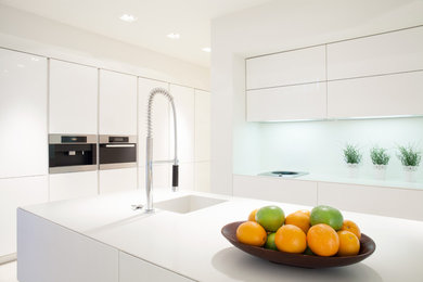 Example of a minimalist eat-in kitchen design in Los Angeles with white cabinets, white backsplash, an island and white countertops