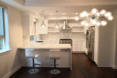 Example of a mid-sized transitional u-shaped vinyl floor and brown floor eat-in kitchen design in Los Angeles with a single-bowl sink, recessed-panel cabinets, white cabinets, solid surface countertops, white backsplash, marble backsplash, stainless steel appliances, a peninsula and white countertops