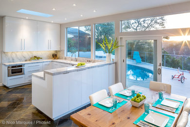 Medium sized modern u-shaped kitchen/diner in Los Angeles with a submerged sink, flat-panel cabinets, white cabinets, marble worktops, grey splashback, stainless steel appliances, slate flooring and an island.