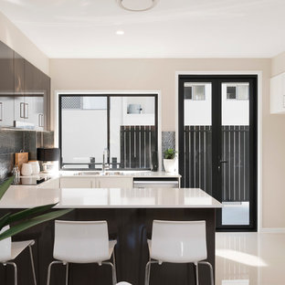 Photo of a small modern u-shaped open plan kitchen in Brisbane with a double-bowl sink, flat-panel cabinets, quartz benchtops, metallic splashback, ceramic splashback, stainless steel appliances, porcelain floors, a peninsula and white cabinets.