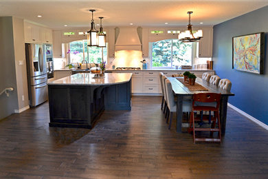 Inredning av ett kök, med en rustik diskho, skåp i shakerstil, vita skåp, bänkskiva i kvarts, vitt stänkskydd, mörkt trägolv och en köksö