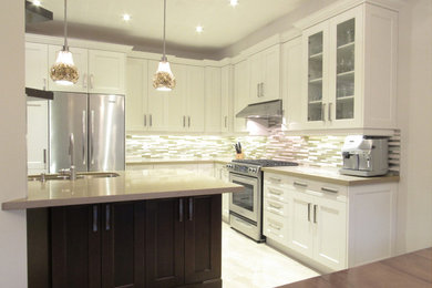 Mid-sized transitional l-shaped ceramic tile eat-in kitchen photo in Toronto with an undermount sink, flat-panel cabinets, white cabinets, quartz countertops, beige backsplash, glass tile backsplash, stainless steel appliances and an island