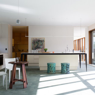 Design ideas for an expansive modern l-shaped open plan kitchen in Other with a double-bowl sink, beige cabinets, solid surface benchtops, grey splashback, porcelain splashback, black appliances, porcelain floors, with island, green floor and white benchtop.