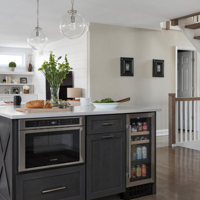 Inspiration for a mid-sized transitional u-shaped medium tone wood floor and gray floor open concept kitchen remodel in Chicago with a farmhouse sink, shaker cabinets, white cabinets, quartz countertops, white backsplash, marble backsplash, stainless steel appliances, an island and gray countertops