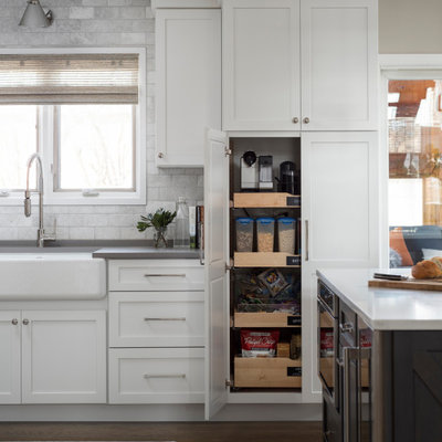 Open concept kitchen - mid-sized transitional u-shaped medium tone wood floor and gray floor open concept kitchen idea in Chicago with a farmhouse sink, shaker cabinets, white cabinets, quartz countertops, white backsplash, marble backsplash, stainless steel appliances, an island and gray countertops