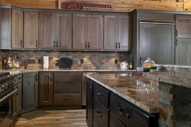 Eat-in kitchen - mid-sized rustic l-shaped medium tone wood floor and brown floor eat-in kitchen idea in Other with an undermount sink, shaker cabinets, medium tone wood cabinets, granite countertops, brown backsplash, stone tile backsplash, paneled appliances and an island