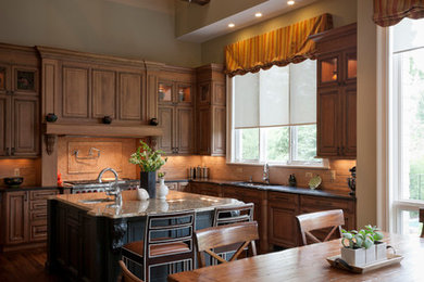 Example of a huge classic single-wall medium tone wood floor eat-in kitchen design in Detroit with an undermount sink, recessed-panel cabinets, medium tone wood cabinets, granite countertops, beige backsplash, stone tile backsplash, stainless steel appliances and an island