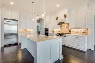 Example of a large classic dark wood floor and brown floor eat-in kitchen design in Birmingham with a farmhouse sink, shaker cabinets, white cabinets, quartz countertops, blue backsplash, brick backsplash, stainless steel appliances and an island