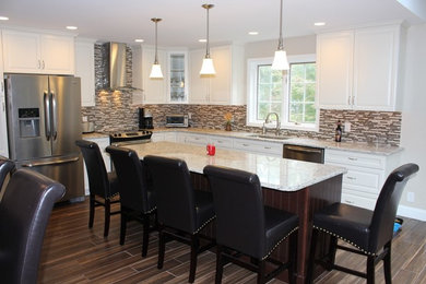 Example of a mid-sized transitional l-shaped ceramic tile eat-in kitchen design in Philadelphia with an undermount sink, raised-panel cabinets, white cabinets, granite countertops, glass tile backsplash, stainless steel appliances and an island
