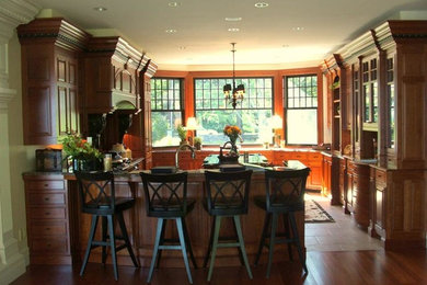 ポートランド(メイン)にある中くらいなトラディショナルスタイルのおしゃれなキッチン (レイズドパネル扉のキャビネット、中間色木目調キャビネット、シルバーの調理設備、無垢フローリング) の写真