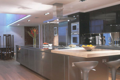Photo of a large contemporary galley open plan kitchen in Other with flat-panel cabinets, grey cabinets, stainless steel worktops and an island.
