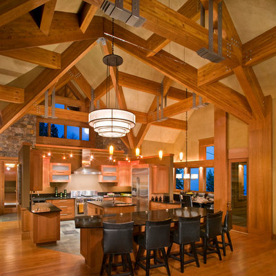 Example of a large mountain style u-shaped medium tone wood floor and brown floor eat-in kitchen design in Other with glass-front cabinets, medium tone wood cabinets, stainless steel appliances, a farmhouse sink, granite countertops, beige backsplash and two islands