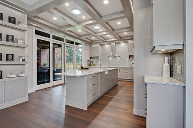 Mid-sized transitional l-shaped medium tone wood floor eat-in kitchen photo in Calgary with an undermount sink, flat-panel cabinets, gray cabinets, marble countertops, gray backsplash, glass tile backsplash, paneled appliances and an island