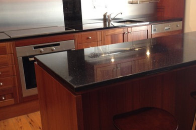 Immagine di una cucina minimalista con ante in legno bruno e top in granito
